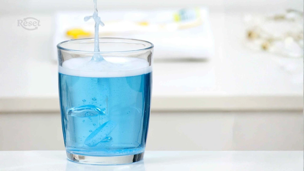 tableta cae dentro de un vaso con agua que se torna azul fondo blanco ¿Rinde lo mismo que un líquido? Cómo funcionan las tabletas (o pastillas) de limpieza reset